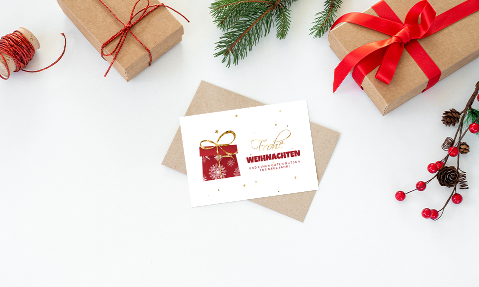 Festliche Weihnachtskarte in weiß, Design rotes Geschenk, Grüße in geschwungener Schrift