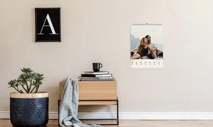 Wochenkalender, Fotokalender, Motiv verliebtes Paar in einem Ruderboot, hängt über einer Ablage mit Kaffeetasse, Bücher und einer Kuscheldecke