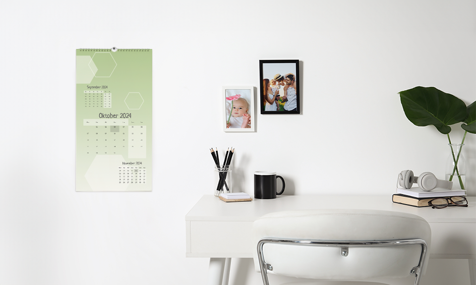 Eine Wand mit Wandkalender und gerahmten Fotos. Das Kalendarium ist grün
