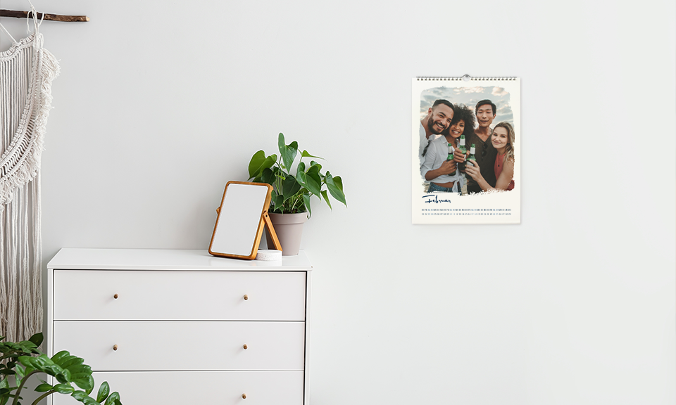 Wandkalender neben weißer Kommode, Pflanze und Spiegel auf Kommode