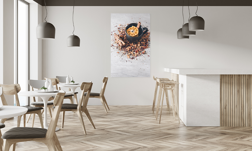 Café mit Tischen und Stühlen, im Hintergrund Klebefolie für Wandgestaltung, Motiv ist Tasse mit Zimtstangen und Orangenscheibe
